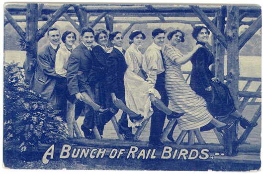 c1910 Photo PC People on RAILROAD BUNCH OF RAIL BIRDS: This is a vintage circa 1910 real photo print postcard. Some Victorian/Edwardian young men and women standing chorus-line-style. Titled A BUNCH OF RAIL BIRDS. Theochrom, Series 1230. Blue tint. SIZE: 