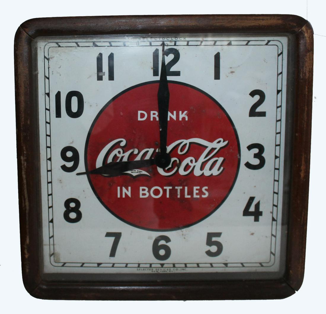 Coca Cola Clock: Attractive clock in wooden case with metal face bearing the iconic Drink Coca Cola in Bottles emblem. Selecto Clock by Selected Services, Inc. New York. Some discoloration and staining on face. Scuffi