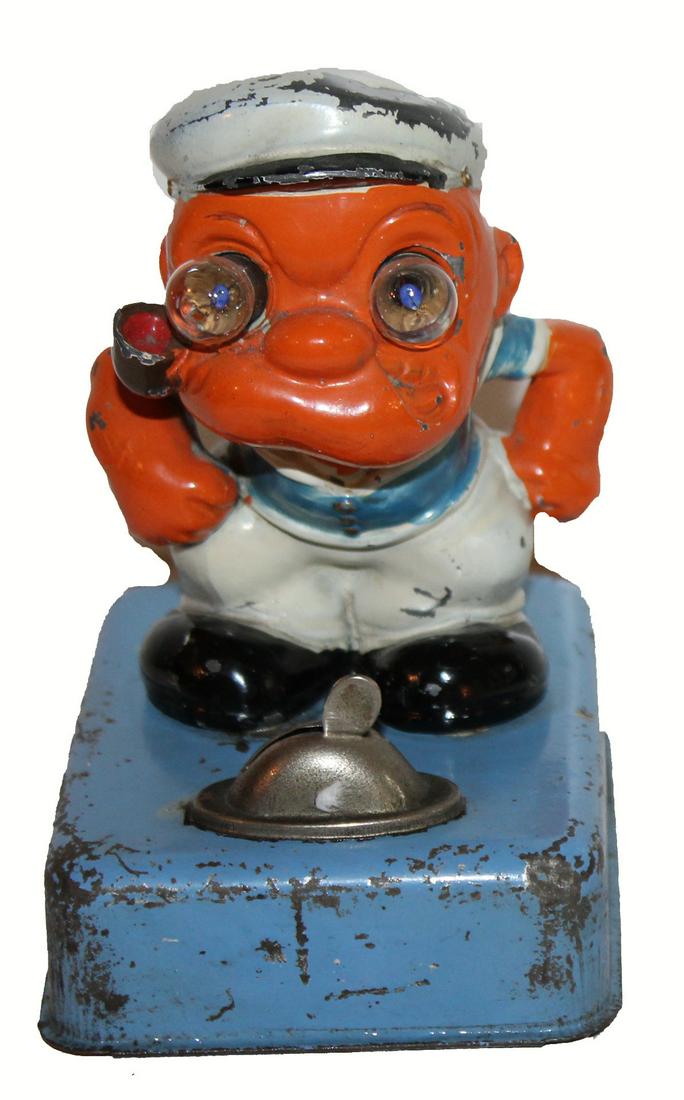 Popeye Toy: Small Popeye figure on stand that houses a battery compartment. His eyes are small light bulbs. There is rust in the battery compartment. Overall wear as noted in photo. Metal construction. No mfg. in