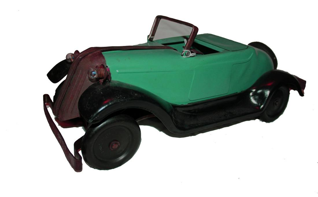Large Model Convertible: Large, heavy pressed steel convertible with keywind mechanism underneath car that drives all four wheels. Front wheels turn from side to side. Two headlights on front. Continental kit on back. Two-ton