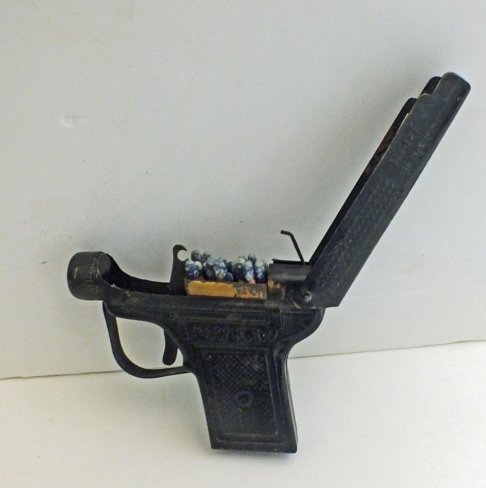 Novelty tin match holder in the shape of a revolver.: Novelty tin match holder in the shape of a revolver. "Browning" embossed on one side, "K. Tomito" on the other. Marked made in Japan on both sides of barrel. Squeeze trigger and top opens to reveal ma