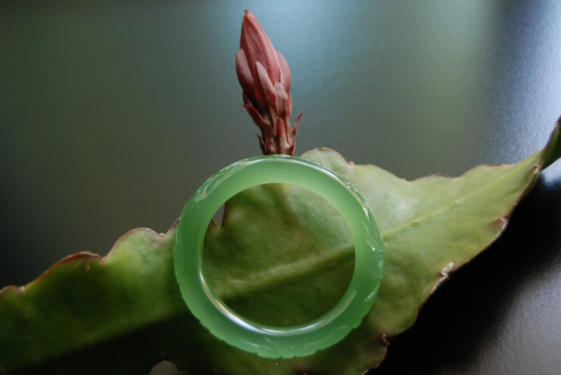 A translucent and exquisite light green colored jadeite: A very fine and exquisite jade bangle. The patterns on this bangle are very beautiful and elegant, they depict two dragons playing with a pearl. Under different circumstances of lighting, the colors w