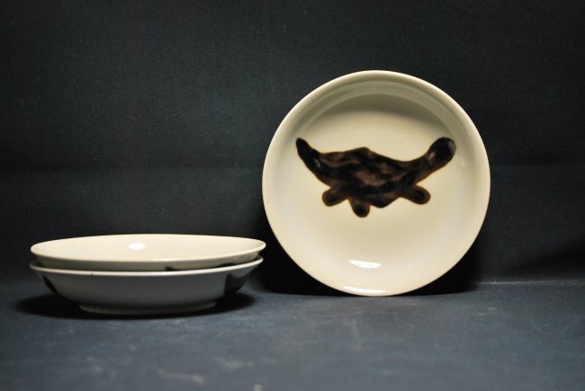 A lot of three copper-red fish dishes: The exterior decorated with three evenly-spaced fish in rich copper-red thinning at the top and pooling at the bottom,the interior glazed white. Each dish has a mark. Diameter 7.1 in/each