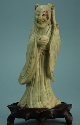 A Ming Dynasty soapstone Buddha: This piece is very well carved. The figure is depicted holding a peach. The wooden stand is made from huanghuali. Height 8 in