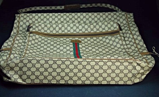 A Gucci monogram canvas garment bag: Monogram Canvas garment bag with tan leather trim and oval patch for monogram. This piece is a second hand item, but it is in a good condition. The trademark is lost. Length 120 cm x 63cm x 12cm