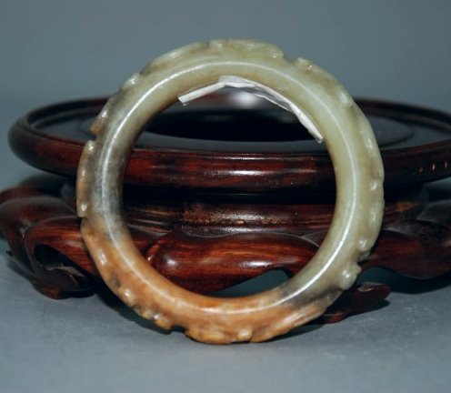 A Han Dynasty carved jade bangle: This jade bangle is very particular, half the bangle is a different shade of jade. There are two dragons carved onto the bangle. This piece was auctioned in San Francisco's Bonham's auction. Diameter 