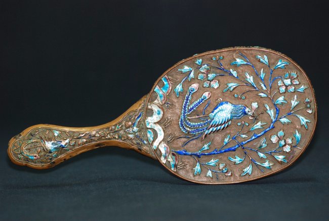 A 19th century Chinese silver and enamel mirror: This piece is decorated with an assortment of enamel flowers and birds. Width 26 cm, Length 11 cm