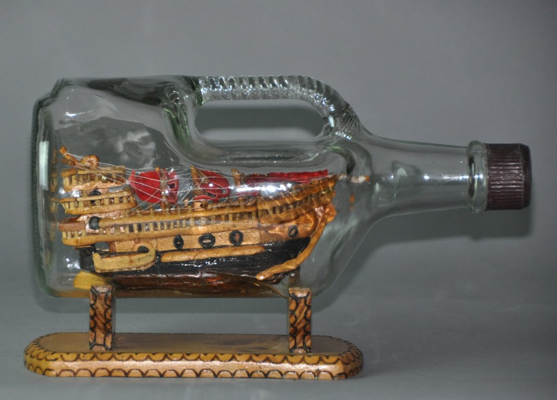 A glass bottle fitted with a wooden boat: Glass bottles fitted with a wooden boat.L:30cm .H:18 cm.