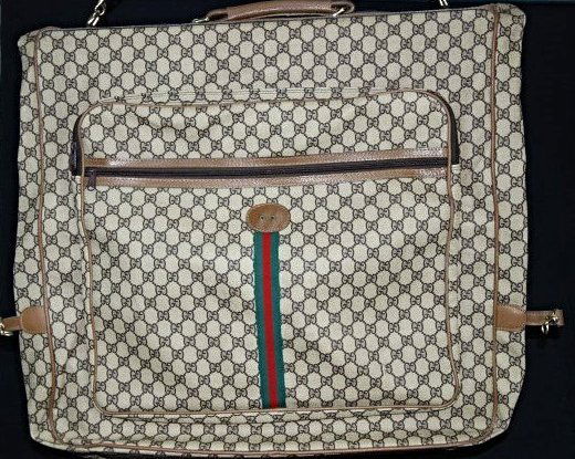 A Gucci monogram canvas garment bag: Monogram Canvas garment bag with tan leather trim and oval patch for monogram. This piece is a second hand item, but it is in a good condition. The trademark is lost. Length 120 cm x 63cm x 12cm