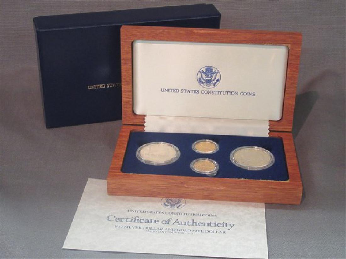 1987 US Gold And Silver Constitution Coin Set: A 1987 Six (6) Piece gold and silver US Constitution coin set. Including Two (2) $5 gold and Four (4) $1 Silver. Housed in a hardwood box.