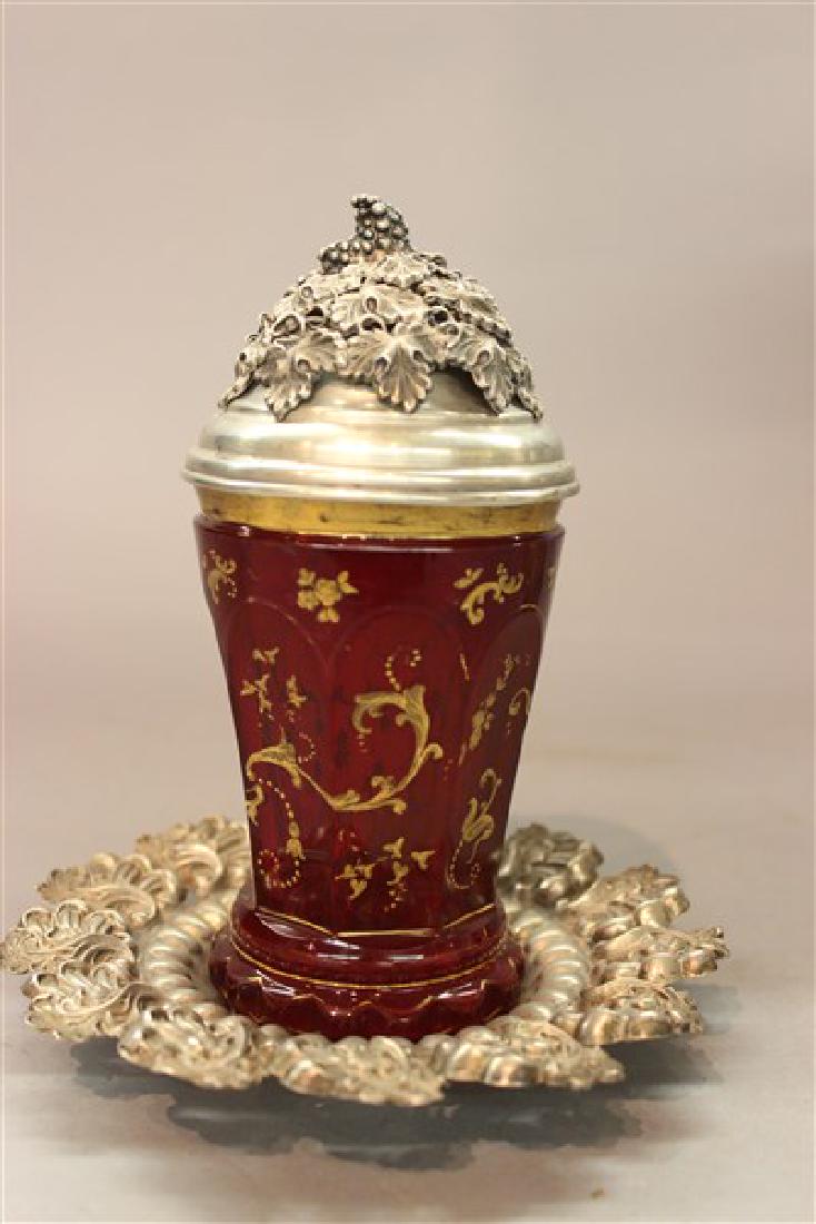 19th c. Moser Covered Jar with Vienna Silver: A fine Moser ruby glass jar with Vienna, Austrian highly ornate silver lid and underplate. Both pieces Hallmarked for Austria with maker's mark AR. Mid 19th century. Dimensions: 7" X 6" t.w.: 5.1 avg.