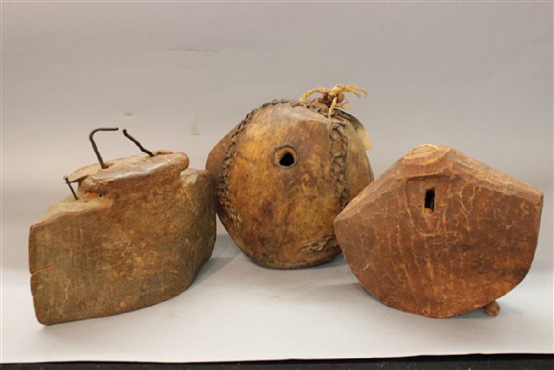 Three (3) Carved Wood And Hide Camel Bells: Three (3) carved wood African and Balinese bells. African bell in center covered in hide. Dimensions: 9" X 9" largest. Provenance: From the collection of the late Mr. Paul Kramer, Chicago, IL.