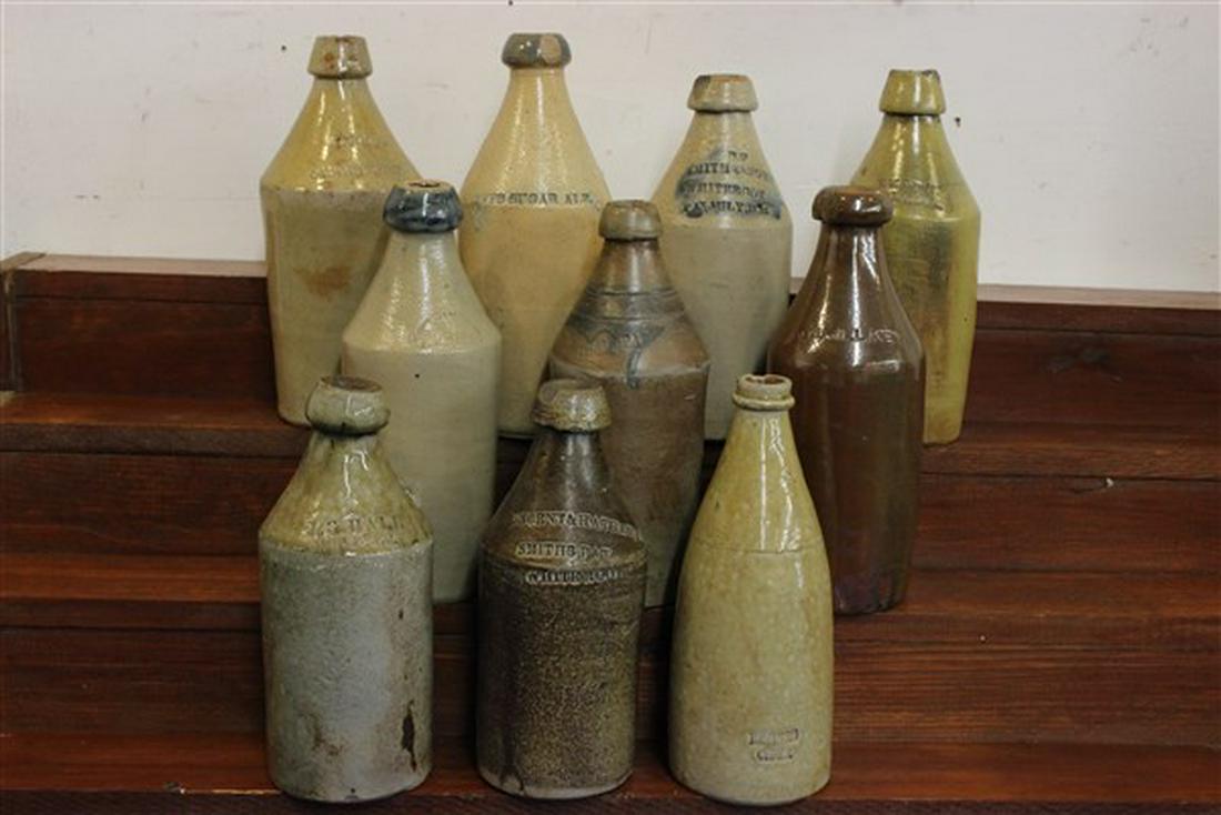 Ten (10) Stoneware Beer Bottles: Ten (10) stoneware beer bottles. Various makers, all having chips or hairline cracks. Dimensions: 9 1/2"- 10 1/2" h.