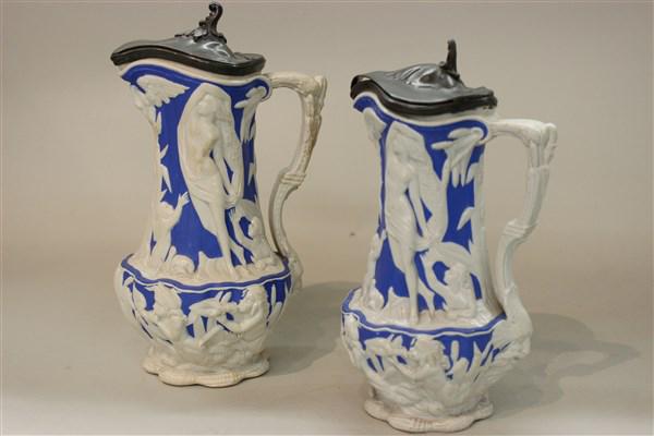Chas. Meigh Ironstone High Relief Jugs: Two (2) Chas. Meigh white ironstone porcelains jugs. Highly ornate relief work with Putti and maidens with pewter lids. Dimensions: 9" and 10" heights