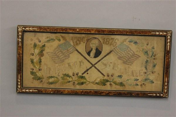 Centennial 1776-1876 American Flag Needlepoint: A Centennial piece depicting President George Washington among with Crossed U.S. Flags. Reads "In Honor Shall Wave" Dimensions: 10" X 22 1/2" framed