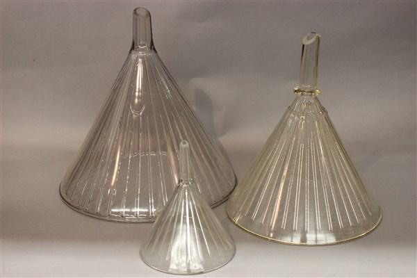 Three Pharmaceutical Glass Funnels: Three old pharmaceutical or science lab funnels. One having a purple tone (largest). Middle size funnel marked Mooney's Patent. Dimensions: 13 1/2" X 12" largest.