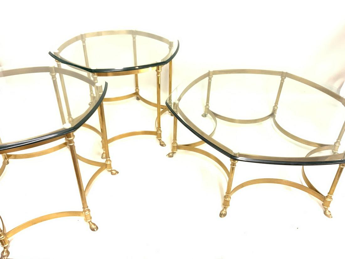 Trois French Brass Hoof Foot Cocktail Tables: A trio of three French brass hoof foot cocktail tables with glass tops. Fine condition. High quality mid century period. One coffee low table and two side tables. Dimensions: 22" X 31" and 15" X 54"d