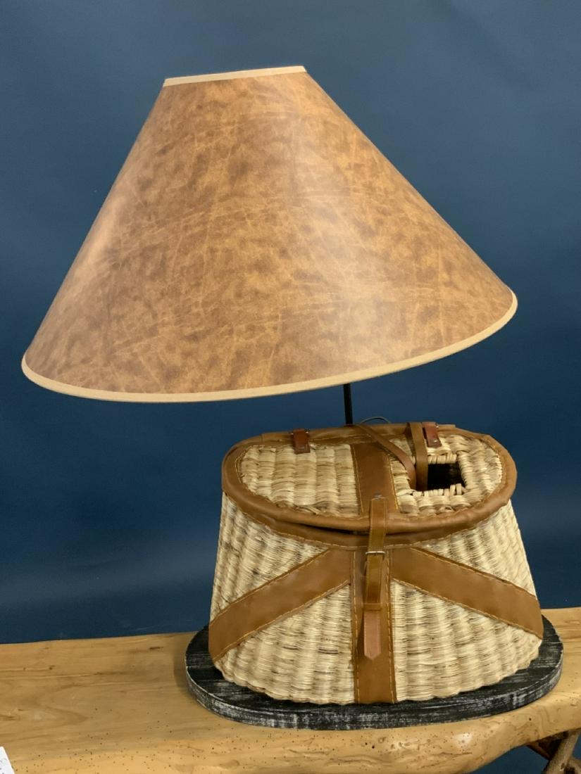 Fishing Creel Decorative Table Lamp: A figural fishing creel table lamp. 23" d shade with black silhouette type fish swimming along interior. Excellent quality lamp. Dimensions: 30" X 20" X 10"