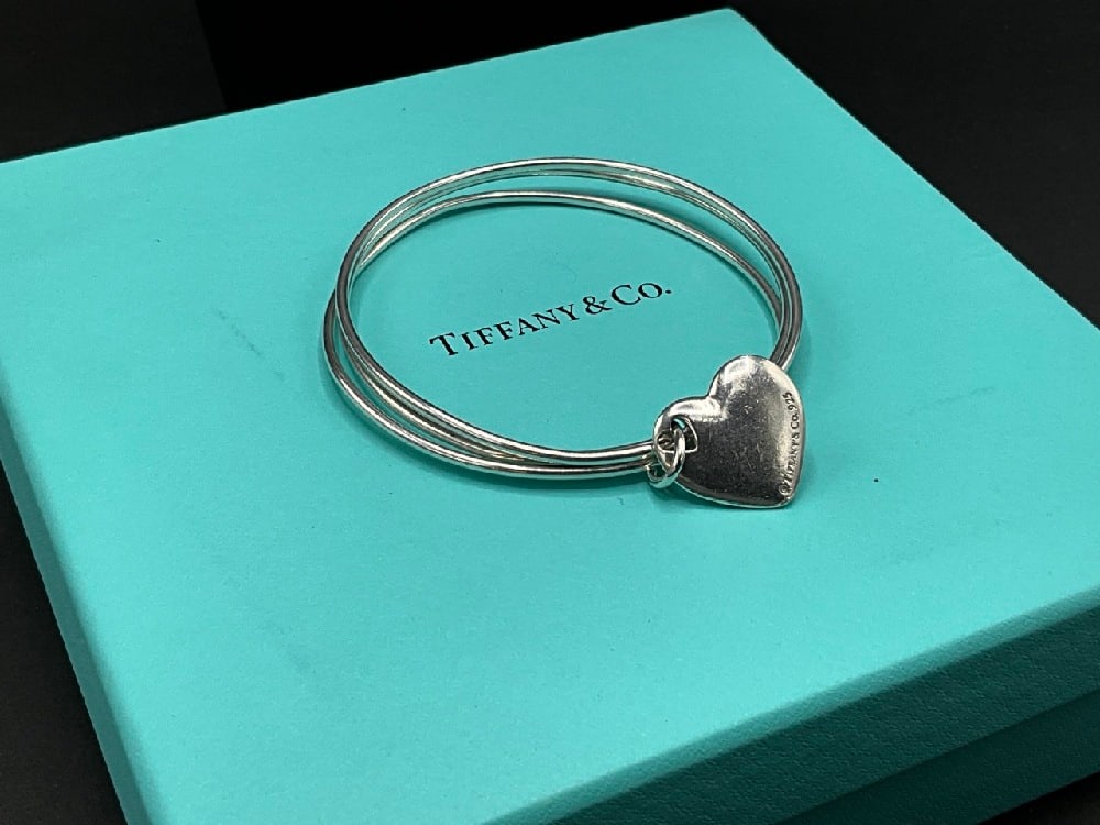 Tiffany & Co. Three Bangle Bracelet w/ Dangly Heart Charm: Tiffany & Co. Sterling Silver Three Bangle Bracelet with Dangly Heart Charm. Box included. Total weight: 24 grams. Dimensions: 2 1/2” d