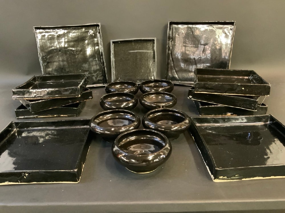 1960's Art Pottery Black Square Plates with Bowls 18 pcs: 1960's Art Pottery Black Square Plates with Bowls 18 pcs. Signed illegibly. Dimensions: Bowls 5” D x 2 1/2” H, Sm. Plate 8” x 8”, Medium 9” x 9”, Larger Plate 10 1/