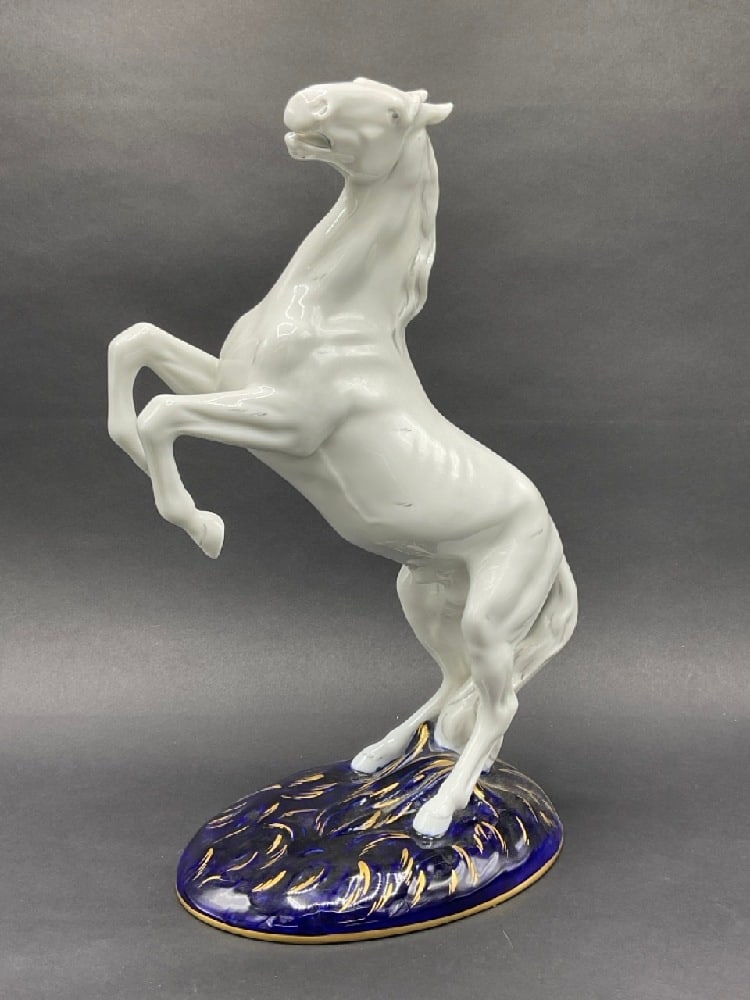 Royal Dux Porcelain Horse Statue: Royal Dux Porcelain Horse Statue. Horse standing on hind legs. A white matte bisque with cobalt blue glazed base.Dimensions: 14 1/2” x 10”