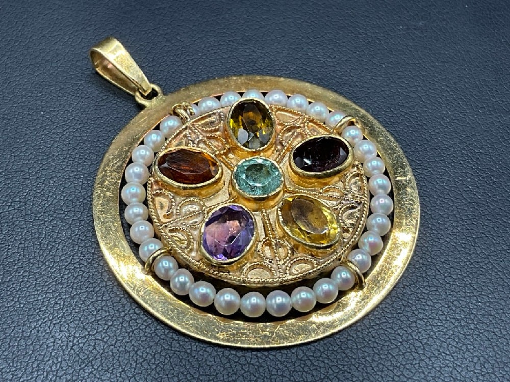 18K Yellow Gold Gemstone Circular Disc Pendant: An 18K yellow gold multi-gemstone circular disc pendant having a pearl border with citrine, garnet, amethyst and aquamarine stones. Total weight: 14.95 grams. Dimensions: 1 5/8” Diameter.