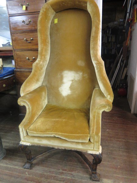 George III Style Hall Porter's Chair: A Baroque George III style Hall Porter's chair, the valanced shaped tall upholstered back with padded sides and scrolled arms over a loose set cushion, tassled seat rail, the whole raised on angular s