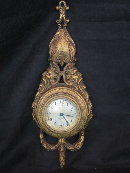 Seth Thomas Roccoco Style Wall Clock: A Seth Thomas Roccoco style wall clock made of gilted metal and wood. Dimensions: 19" X 6 1/2"Inv.152