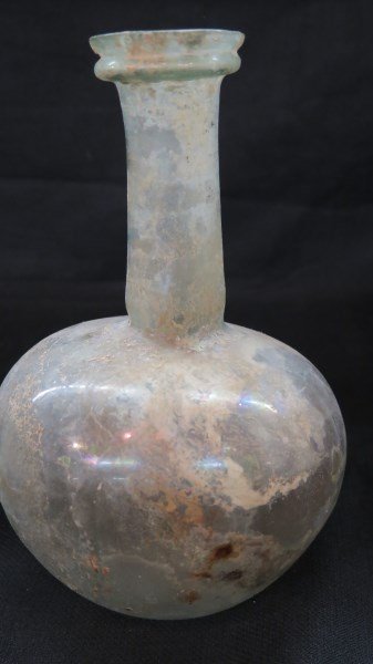 Ancient Roman Glass Large Bottle: An Ancient Roman Glass bottle. Larger size measuring 8 1/4" Height and 5" width. Very Very thin glass, undamaged. Green iridescent coloring.