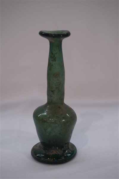 Ancient Roman Glass Green Bottle: An Ancient Roman glass green bottle. Dimensions: 3 1/4" X 1 1/4" Provenance: Collection of the late Mr. Hugh D. Farley. Mr. Farley acquired the pieces while he was the Director of the US Foreign Aid P