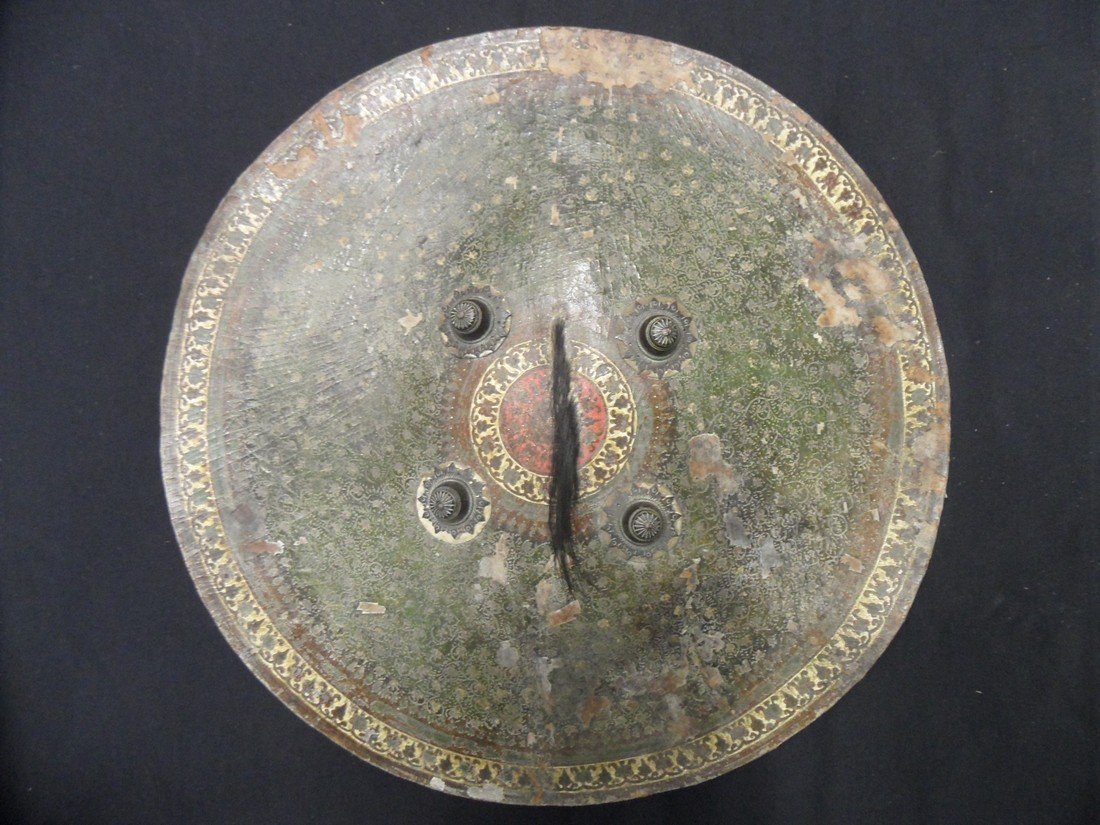 AN INDIAN CIRCULAR HIDE SHIELD (DHAL), RAJASTHAN, 19TH: AN INDIAN CIRCULAR HIDE SHIELD (DHAL), RAJASTHAN, 19TH CENTURY of characteristic form, the inside painted red with a gold border, with an early pad and later enarmes, the outside set with four pronoun