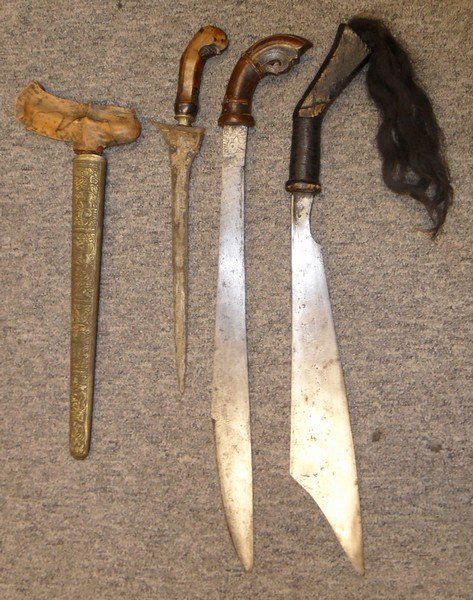 THREE SOUTH EAST ASIAN DAGGERS, 19TH/20TH CENTURIES: THREE SOUTH EAST ASIAN DAGGERS, 19TH/20TH CENTURIES comprising a Malaysian keris, with pattern welded blade, carved hardwood grip, in its scabbard; and two machetes with hardwood hilts, one with black
