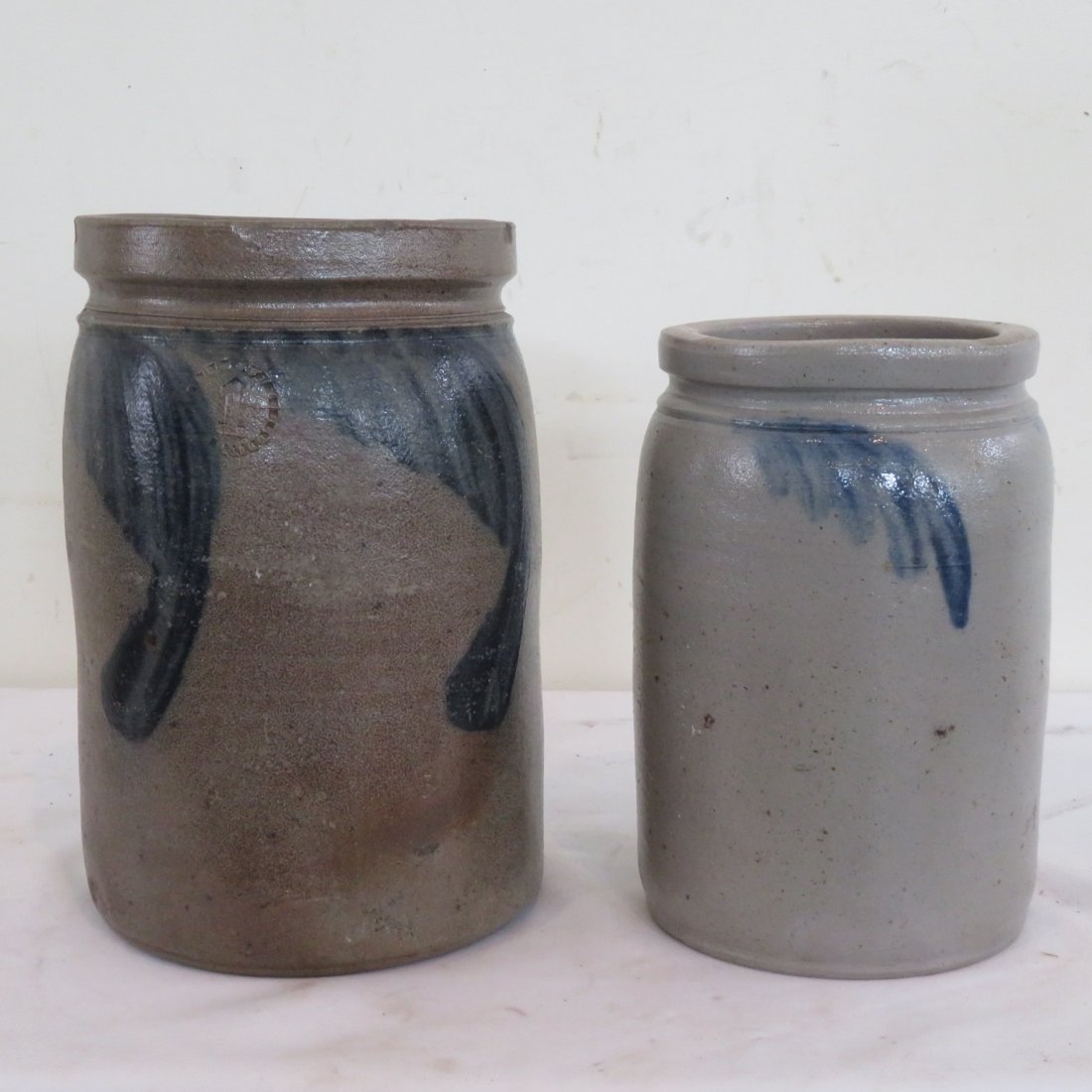 2 Eastern PA stoneware jars: 2 Eastern PA stoneware jars, 1 gal is 9.5"H x 6.5"W & half gal. is 8.25"H x 5.25"W, freehand decorations