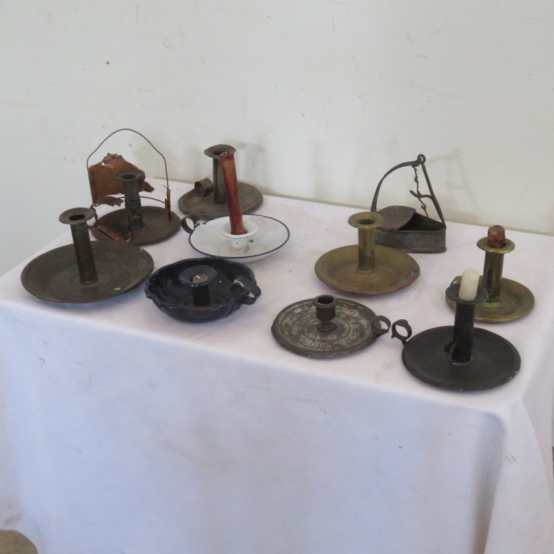 10 pieces of tin lighting: 10 pieces of tin lighting includes one betty lamp with hanger, 7 tin saucer base chambersticks and 2 enameled saucer base chambersticks, largest is 4" tall and the saucer is 7" diameter