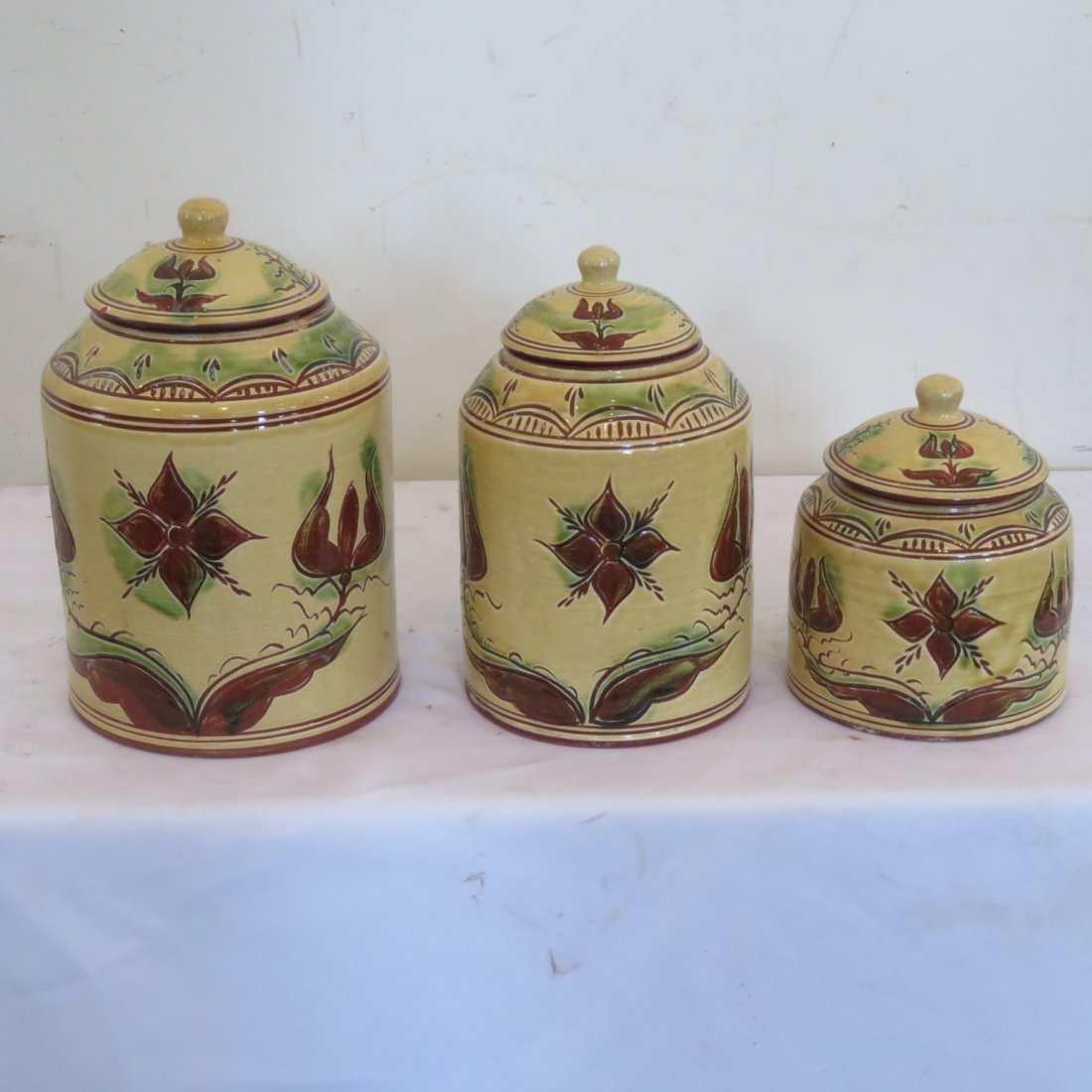 Contemporary 3 pc. redware canister set: Contemporary redware 3 piece canister set with tulip motif signed SJ Pottery, Bethel, Missouri. Largest canister 11"H x 5 3/4" dia.