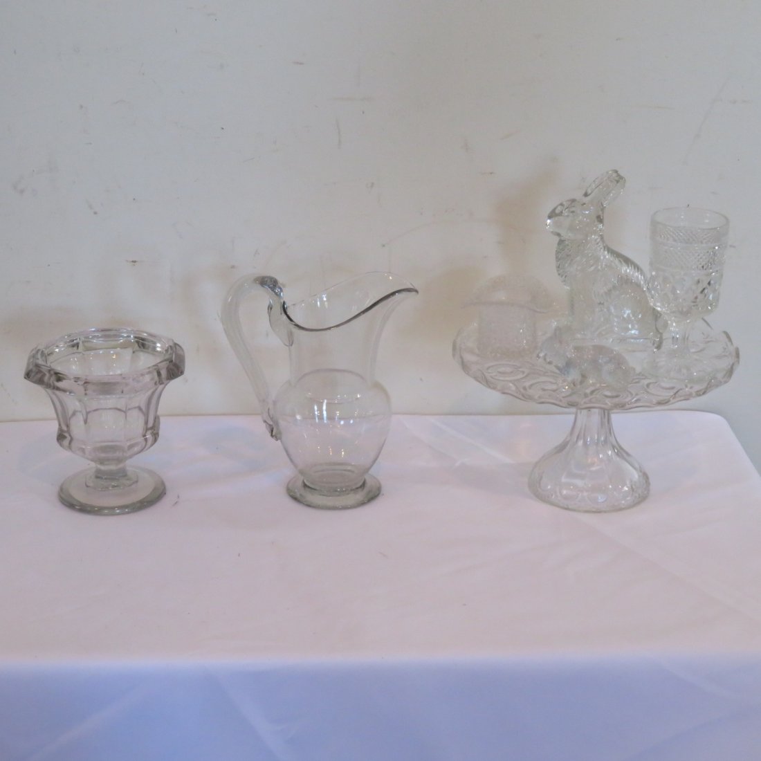 Group of 7 glass pieces: Group of 7 glass pieces: includes Flint glass spill, hand blown pitcher 8"H, patterned glass cake stand, juice glass, 2 glass bunnies (1 is a candy container), and glass hat toothpick holder