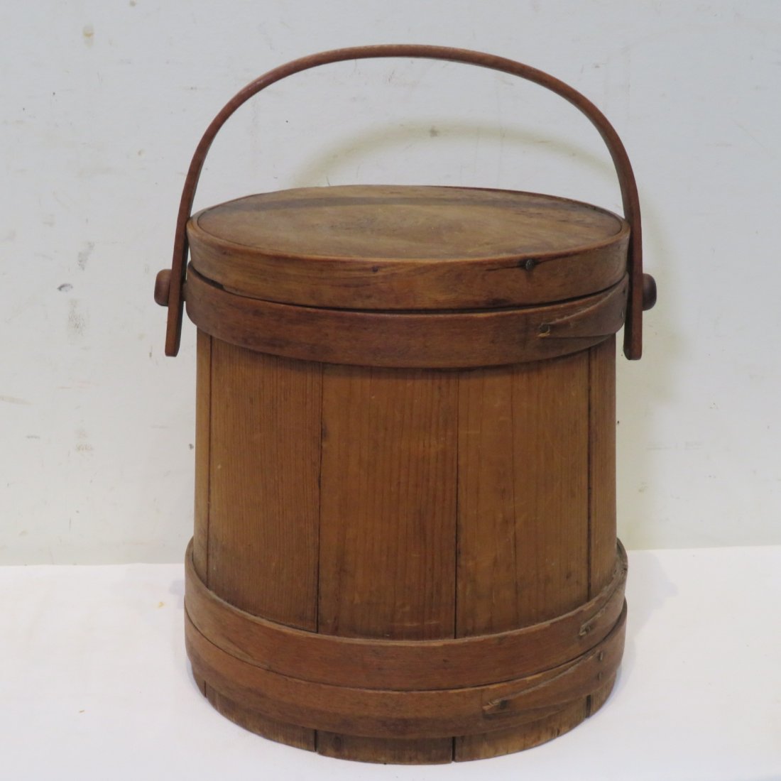 Early wood firkin with wood bands: Early wood firkin with wood bands that are nailed, old natural surface, wood handle, and a lid, 9.5"H x 8.5"D (top) and 9"D (bottom)