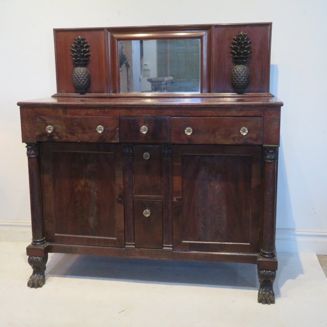 Period Empire mahogany side board with backsplash: Period Empire mahogany side board with backsplash that has carved pineapples and a mirror, drawers are dovetailed, 2 middle drawers are for wine bottles and have dividers for 3 bottles, 3 additional d