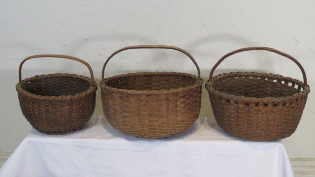 3 round gathering baskets in old dark natural patina: 3 round gathering baskets in old dark natural patina with wooden handles, largest is 9"T (w/o handle) x 17.5"W x 16"D