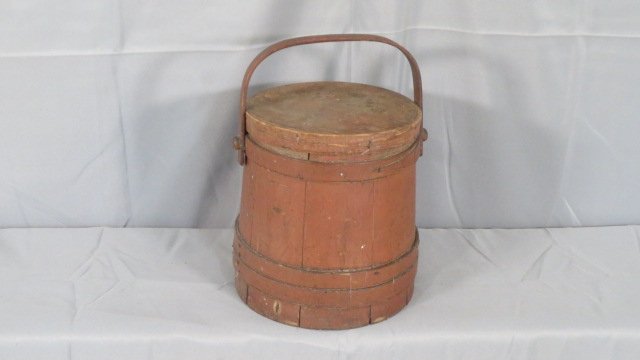 Wood firkin in old red paint: Wood firkin in old red paint. 10"t. x 8 1/2" dia. at top, 9 1/2" dia. at bottom, nailed straps with staple on end