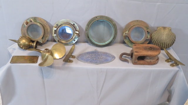 12 misc. items includes Nautical: 12 misc. items including 4 brass nautical portholes, a brass propeller, 2 brass boat tie offs, a wood pully with hand wrought hook, a French 1897 metal racing sign and a brass plaque off of a 40 mm 19