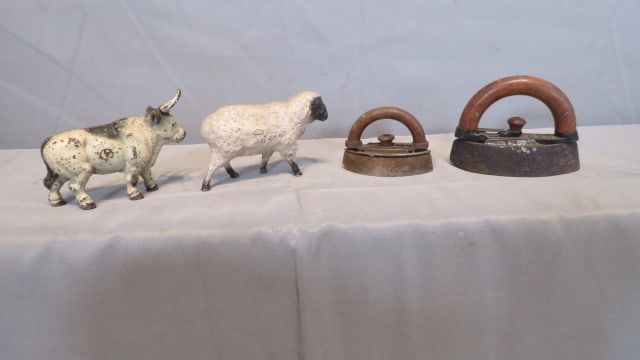 4 iron toys: 4 iron toys, including 2 child's irons with wood handles, largest one is dated 1895, a lamb still bank, and a longhorn steer still bank 3.75"T x 5"L