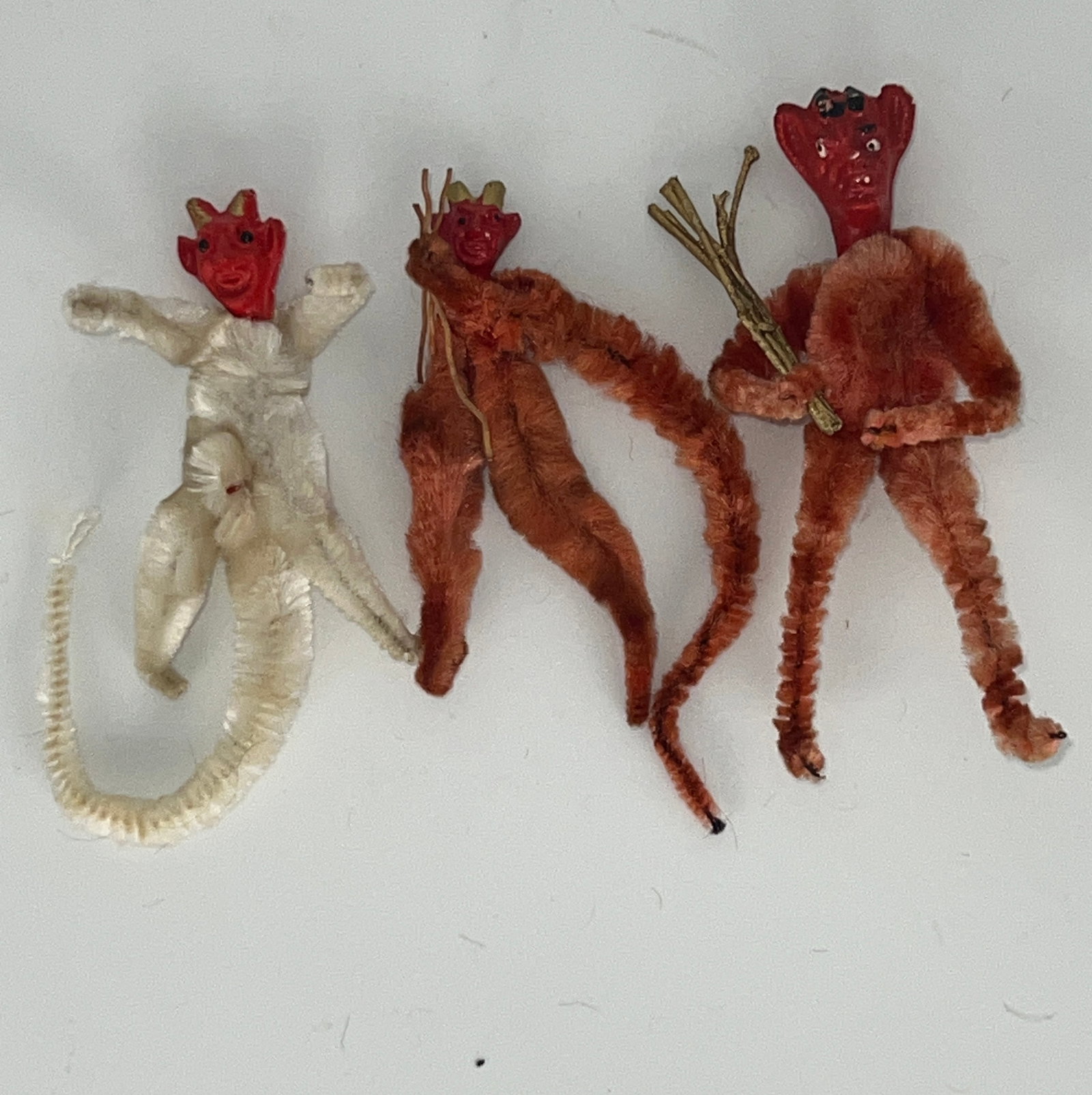 Group of Three Krumpas Ornaments: Group of 3 Krumpas Chenille body ornaments. 2 orange & 1 white. All with red composite head. 2 smallest w/longer tails. Tallest 4"T. Smallest 3"T