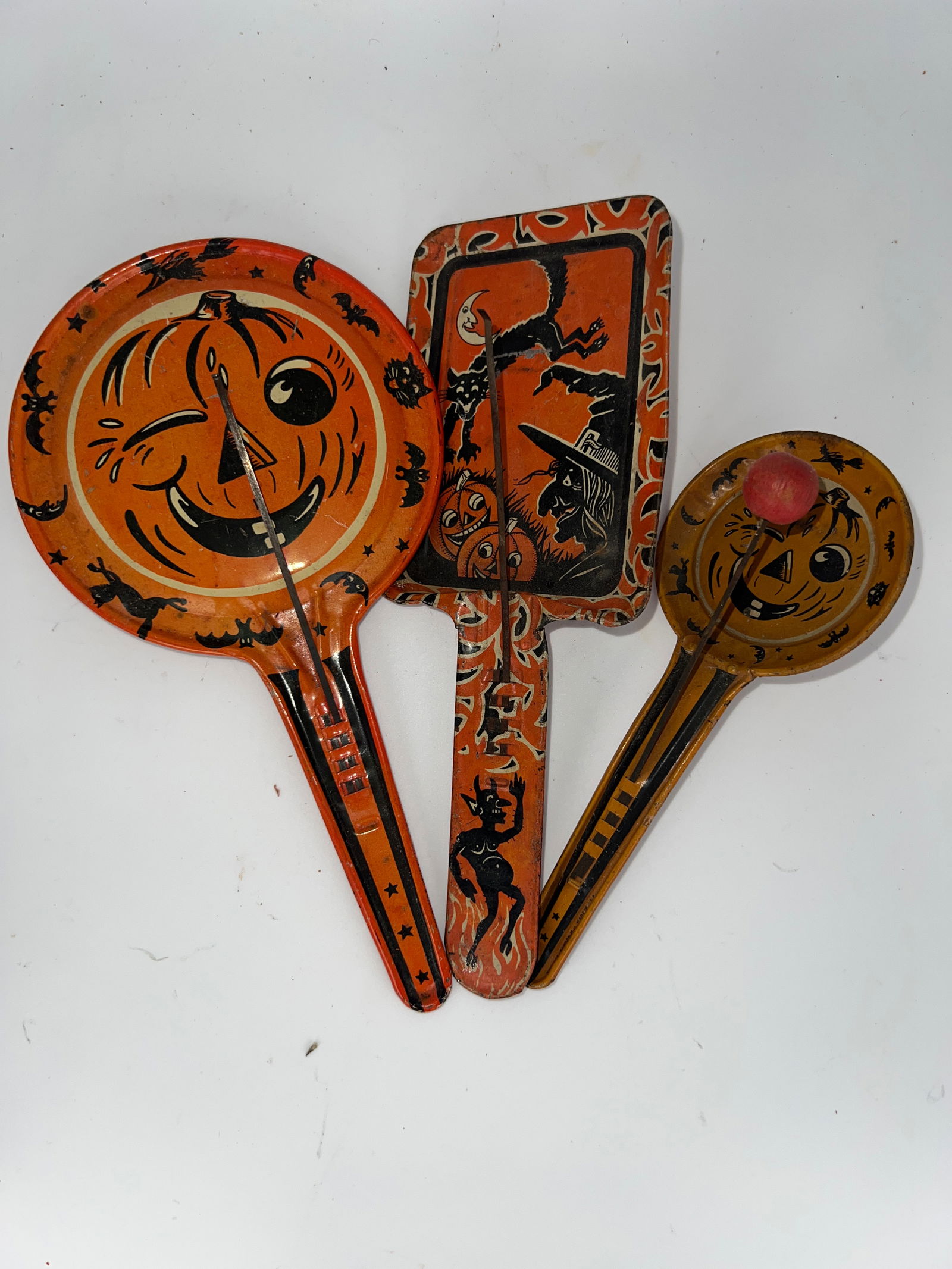 Three Clacker Noise Makers: Three tin litho clacker noise makers: 2 round face w/Jack O'Lanterns, witches & black cats, rectangle noise makers has black cats & black Krumpas figure on handle. 2 are missing wooden clacker ball. L
