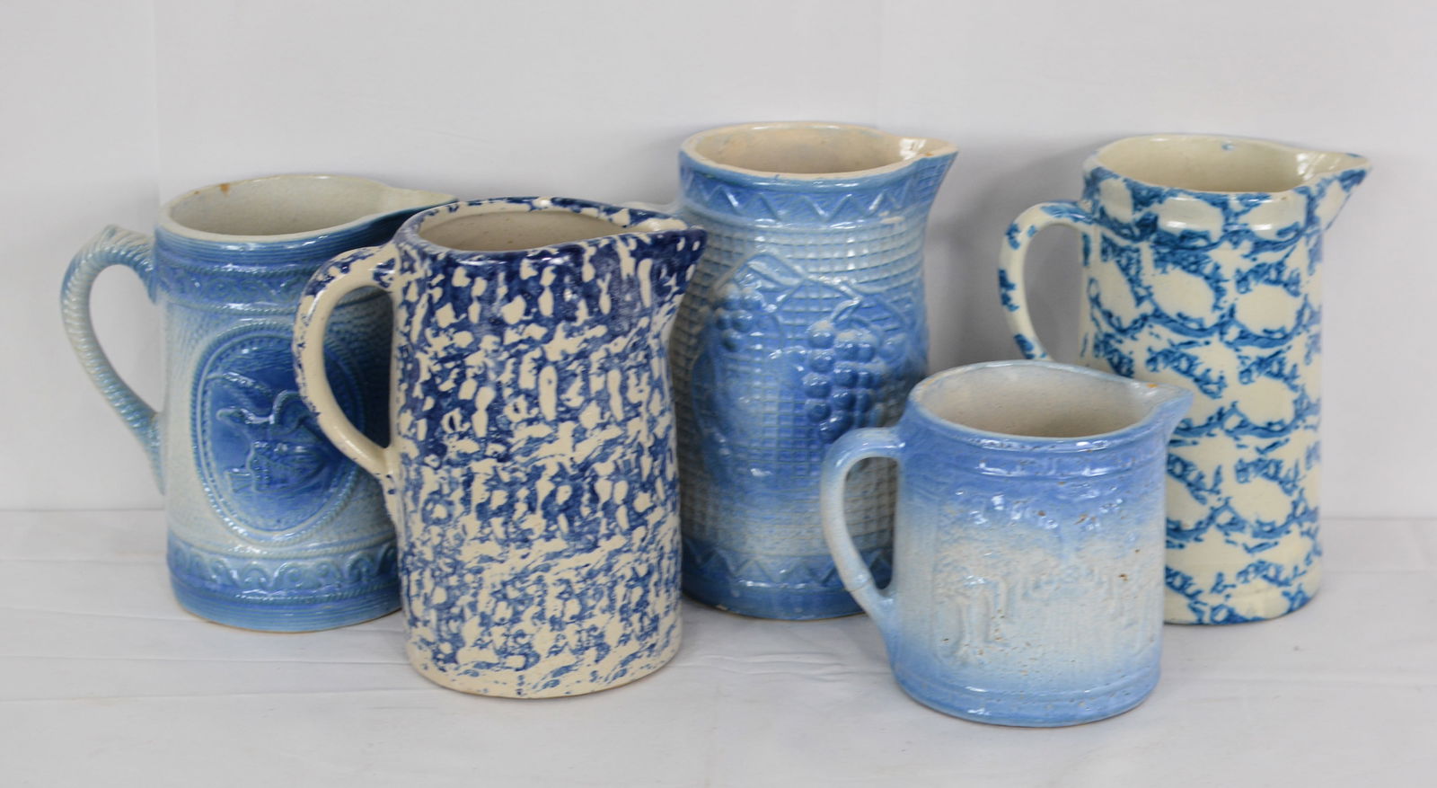 5 Stoneware pitchers: Blue and white, Spongeware, Eagle with shield and arrows. 5"x11": 5 Stoneware pitchers: Blue and white, Spongeware, Eagle with shield and arrows. 5"x11"