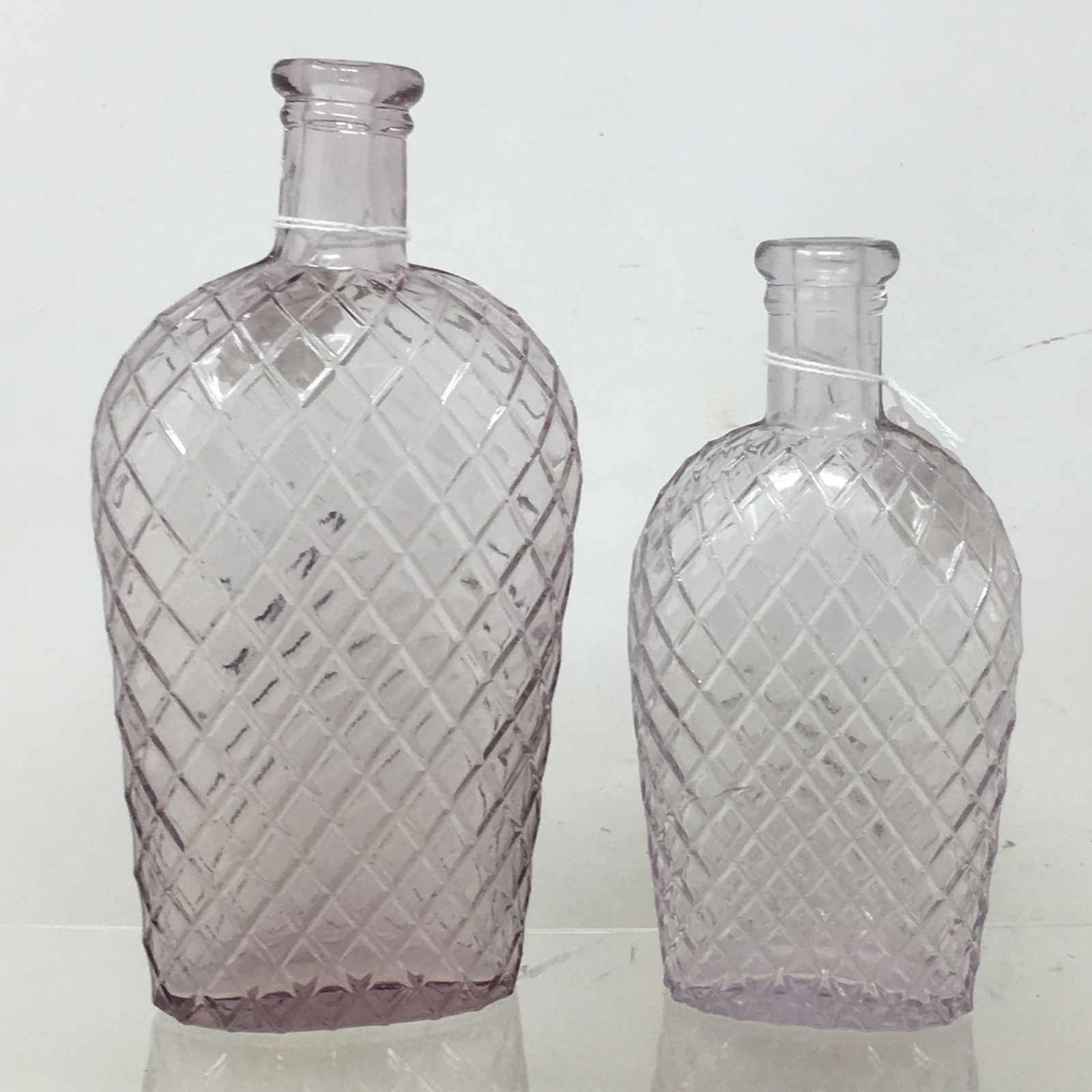 (2) Amethyst Quilted Coffin Flask Liquor Bottles, Large one marked PBW for Point Bottle Works: (2) Amethyst Quilted Coffin Flask Liquor Bottles, Large one marked PBW for Point Bottle Works Company. small one has possible interior defect at neck base that may be from manufacturing. 6 3/8" and