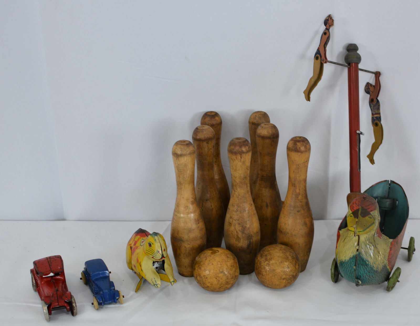 Set of wooden bowling pins & balls, 2 cast iron sedans, acrobats whirly toy, a tin duck & tin: Set of wooden bowling pins & balls, 2 cast iron sedans, acrobats whirly toy, a tin duck & tin rabbit. Tallest 14" Widest 6"