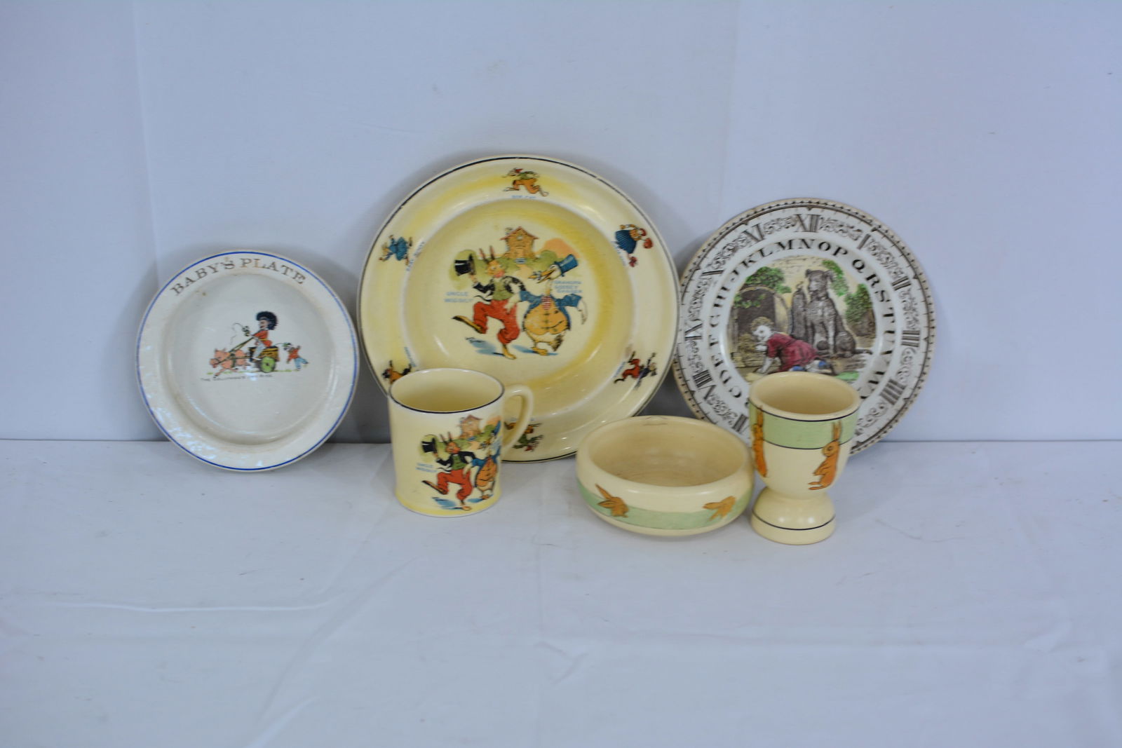 Group of Child's plates includes Rossville bowl & egg cup, Uncle Wiggily bowl & cup, The Gollywogs: Group of Child's plates includes Rossville bowl & egg cup, Uncle Wiggily bowl & cup, The Gollywogs Joy Ride Baby Plate. Largest 8"