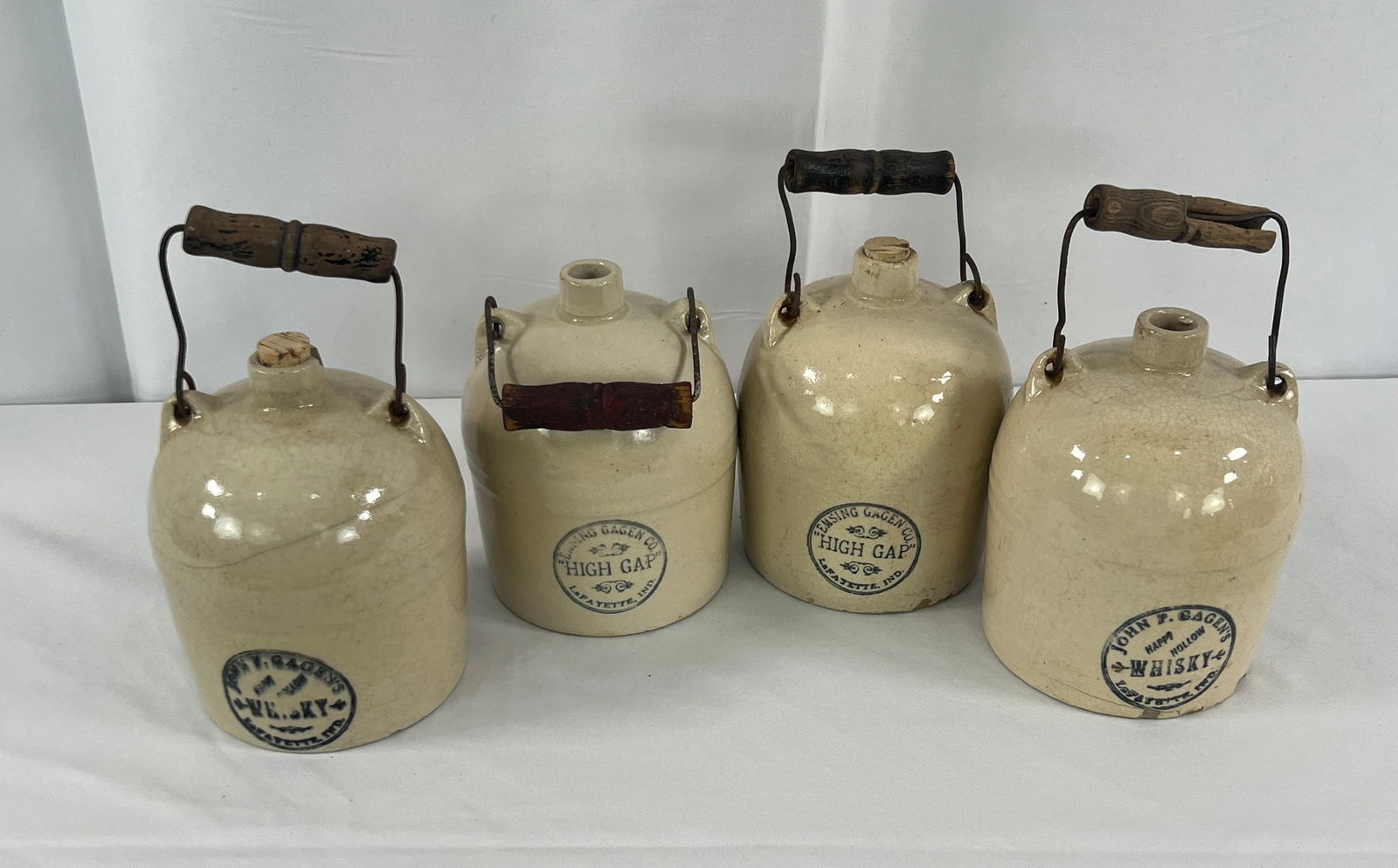 4 Gagens Whisky Stoneware Jugs: 4 Gagens Whisky Stoneware Jugs, John and Emsing Hagen advertising whisky jugs, High Gap and Happy Hallow, Lafayette, IN, stoneware with bail handles, hairlines and chips