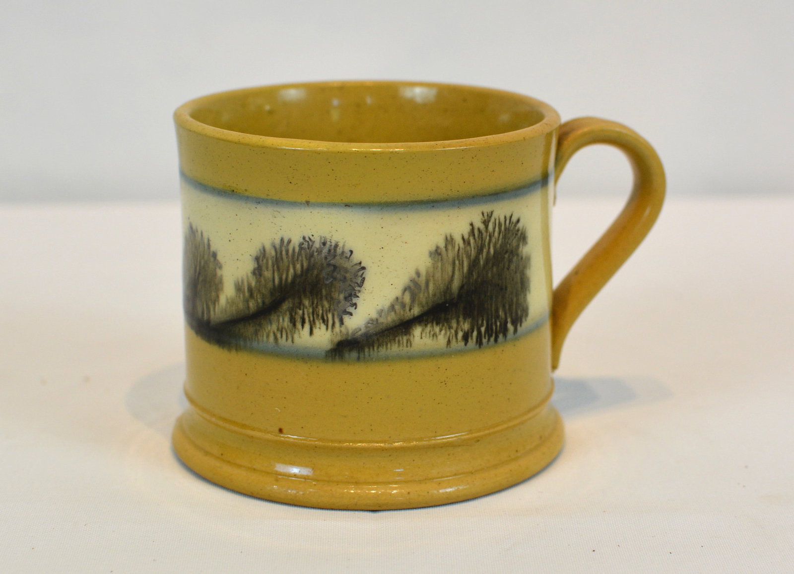 19th Century Mocha ware Child's Mug: Charming 19th-century English mochaware child's mug featuring bold black "seaweed" decoration flowing across a cream-colored slip band. Raised on a molded foot and fitted with an applied handle, this